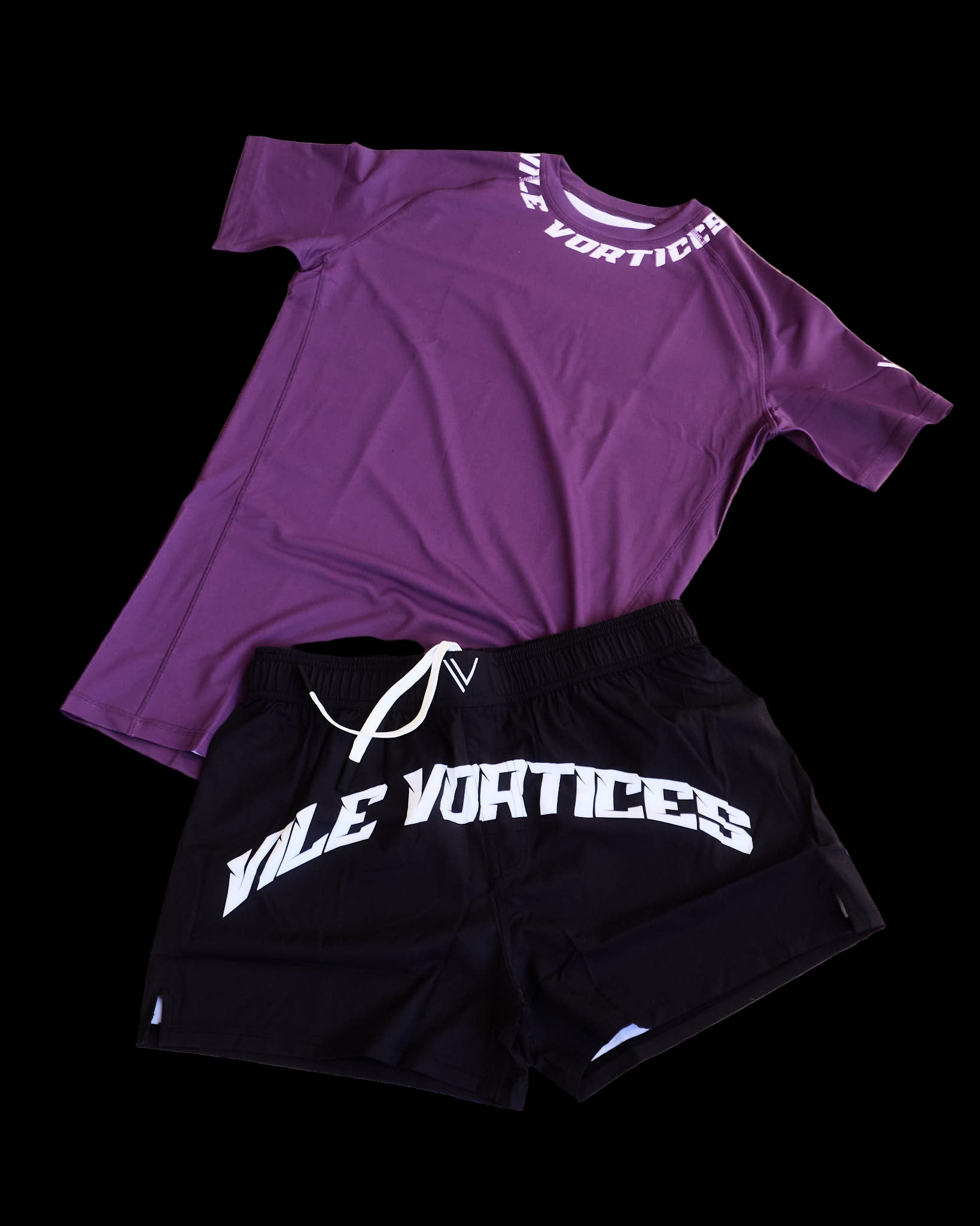 Purple t-shirt and black shorts with 'VIle Vortices' branding on a beige surface